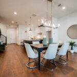 A modern dining area with a kitchen in the background and hardwood floors
