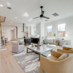 A luxurious living area with comfortable chairs, a coffee table, large windows, and a staircase on the left hand side