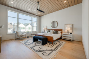 A beautiful bedroom with a large bed, hardwood floors, and large windows